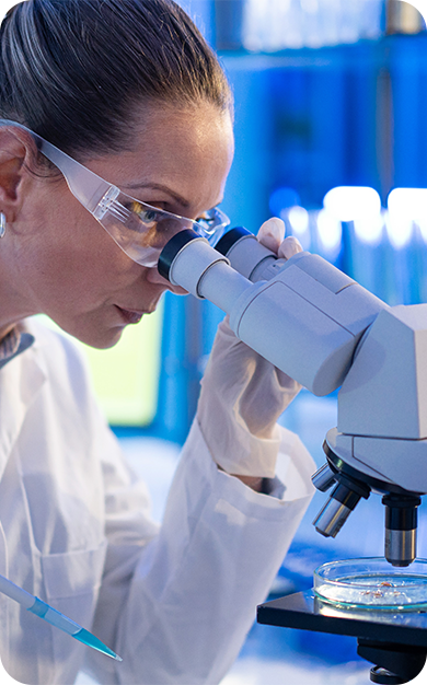 A researcher looking through a microscope to analyze a sample.